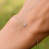 Woman wearing a Classic cable chain bracelet featuring one 4 mm briolette cut aquamarine bezel set in 14k gold