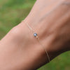 Woman with a Classic cable chain bracelet featuring one 4 mm briolette cut Nantucket blue topaz bezel set in 14k gold