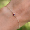 Woman with a Classic cable chain bracelet featuring one 4 mm briolette cut ruby bezel set in 14k gold