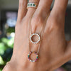 Hand holding two Rosecliff open circle necklaces each with sixteen 2 mm faceted round cut gemstones prong set in 14k gold
