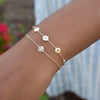 Woman wearing a 14k gold cable chain bracelet featuring 2 birthstones and three 1/4” flat engraved letter discs, spelling Joy