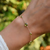 Woman with a Bayberry Grand & Classic cable chain bracelet in 14k gold featuring seven alternating 4 mm and 6 mm peridots