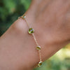 Hand with a Bayberry Grand & Classic cable chain bracelet in 14k gold featuring seven alternating 4 mm and 6 mm peridots