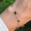 Woman wearing a Bayberry Grand & Classic cable chain bracelet in 14k gold featuring seven alternating 4 mm & 6 mm sapphires