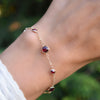 Woman with a Bayberry Grand & Classic 1.17 mm cable chain bracelet in 14k gold featuring seven alternating 4 mm & 6 mm rubies