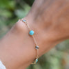 Hand with a gold Bayberry Grand & Classic cable chain bracelet with 4 mm Nantucket blue topaz & 6 mm turquoise gemstones