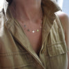 Woman wearing a 14k yellow gold cable chain necklace featuring 1/4” flat discs engraved with letters