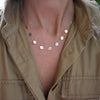 Woman with a 14k yellow gold cable chain necklace featuring 1/4” flat discs engraved with letters