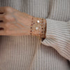 Woman wearing several bracelets including a 14k gold bracelet featuring four 1/4” flat engraved letter discs, spelling XO