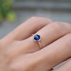 Hand wearing a 1.6 mm wide 14k yellow gold Grand ring featuring one 6 mm briolette cut bezel set sapphire