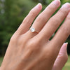 Hand wearing a 1.6 mm wide 14k yellow gold Grand ring featuring one 6 mm briolette cut bezel set moonstone