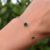 Woman with a Grand & Classic bracelet featuring one 6 mm and four 4 mm briolette Emeralds bezel set in 14k yellow gold