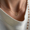 Woman wearing an Adelaide Mini necklace featuring one 1/2” cutout Peace Sign in 14k yellow gold