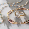 Assorted jewelry including a gold Adelaide paperclip chain pavé bracelet featuring gemstone-encrusted links