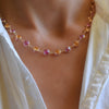 Woman wearing a Sunset Newport Grand necklace featuring alternating 6 mm pink sapphires and citrines bezel set in 14k gold