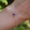 Woman's hand wearing a Grand 1.17 mm cable chain bracelet in 14k gold featuring one 6 mm briolette cut bezel set amethyst