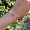 Woman's hand with a Grand 1.17 mm cable chain bracelet in 14k yellow gold featuring one 6 mm briolette cut bezel set amethyst