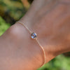 Woman's hand wearing a Grand 1.17 mm cable chain bracelet in 14k gold featuring one 6 mm briolette cut bezel set aquamarine