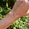 Woman's hand with a Grand 1.17 mm cable chain bracelet in 14k gold featuring one 6 mm briolette cut bezel set aquamarine