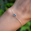 Woman's hand wearing a Grand 1.17 mm cable chain bracelet in 14k gold featuring one 6 mm briolette cut Nantucket blue topaz