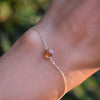 Woman's hand wearing a Grand 1.17 mm cable chain bracelet in 14k gold featuring one 6 mm briolette cut bezel set citrine