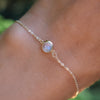 Woman's hand wearing a Grand 1.17 mm cable chain bracelet in 14k gold featuring one 6 mm briolette cut bezel set moonstone