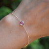 Woman's hand wearing a Grand 1.17 mm cable chain bracelet in 14k gold featuring one 6 mm briolette cut pink sapphire