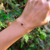 Woman's hand with a Grand 1.17 mm cable chain bracelet in 14k yellow gold featuring one 6 mm briolette cut bezel set ruby