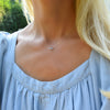 Woman wearing a Grand 14k yellow gold 1.17 mm cable chain necklace featuring one 6 mm briolette cut bezel set aquamarine