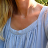 Woman wearing a Grand 14k gold 1.17 mm cable chain necklace featuring one 6 mm briolette cut bezel set Nantucket blue topaz