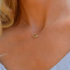 Woman with a Grand 14k yellow gold 1.17 mm cable chain necklace featuring one 6 mm briolette cut bezel set peridot