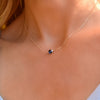 Woman with a Grand 14k yellow gold 1.17 mm cable chain necklace featuring one 6 mm briolette cut bezel set sapphire