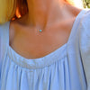 Woman wearing a Grand 14k yellow gold 1.17 mm cable chain necklace featuring one 6 mm briolette cut bezel set turquoise