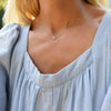 Woman wearing a Grand 14k yellow gold 1.17 mm cable chain necklace featuring one 6 mm briolette cut bezel set white topaz