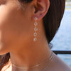 Woman wearing necklaces and a 14k yellow gold Grand stud earring featuring five 6 mm briolette cut bezel set white topaz