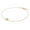 Grand 1.17 mm cable chain bracelet in 14k yellow gold featuring one 6 mm briolette cut bezel set peridot - angled view