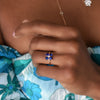 Woman wearing a Greenwich ring featuring four 4 mm round cut gemstones and one 2.1 mm diamond prong set in 14k gold