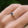 Woman wearing a Greenwich ring featuring one 4 mm faceted round cut alexandrite and one 2.1 mm diamond prong set in 14k gold