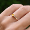 Woman wearing a Greenwich ring featuring one 4 mm faceted round cut citrine and one 2.1 mm diamond prong set in 14k gold