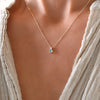 Woman wearing a Greenwich necklace featuring one 4 mm Nantucket blue topaz & one 2.1 mm diamond bezel set in 14k yellow gold