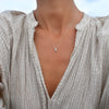 Woman wearing a Greenwich necklace featuring one 4 mm Nantucket blue topaz & one 2.1 mm diamond bezel set in 14k gold