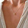 Woman wearing a Greenwich cable chain necklace featuring one 4 mm peridot and one 2.1 mm diamond bezel set in 14k gold