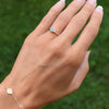 Woman wearing a Greenwich ring featuring one 4 mm round cut Nantucket blue topaz and one 2.1 mm diamond prong set in 14k gold