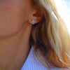 Woman wearing a 14k yellow gold Greenwich 4 Birthstone earring featuring four 4 mm Nantucket blue topaz & one 2.1 mm diamond