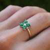 Woman wearing a Greenwich ring featuring four 4 mm faceted round cut emeralds and one 2.1 mm diamond prong set in 14k gold