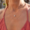 Woman wearing layered gold necklaces including a Greenwich necklace featuring four 4 mm white topaz and one 2.1 mm diamond
