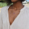 Woman wearing two gold necklaces including a Greenwich necklace featuring five 4 mm amethysts and one 2.1 mm diamond