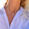 Woman wearing a 14k gold Classic necklace featuring two birthstones and two 1/4” flat letter-engraved discs