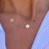 Woman with a 14k gold Classic necklace featuring two birthstones and two 1/4” flat letter-engraved discs