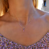 Woman wearing a Providence Ruby vertical bar pendant featuring 3 petite baguette stones set in 14k yellow gold